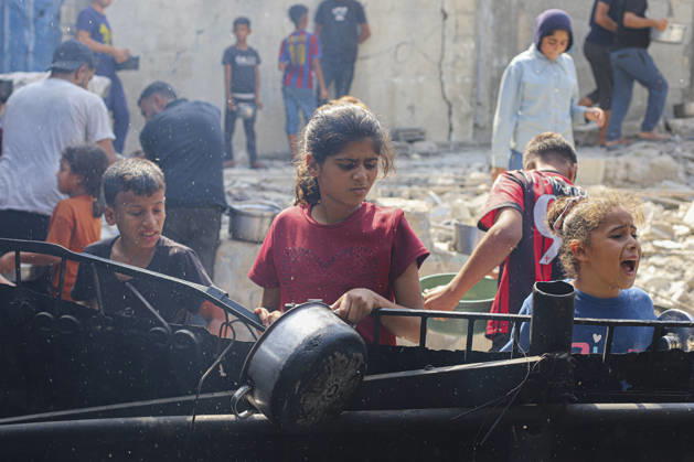 Gaza Palestinians Food Shortages 2026 Palestinian children wait with metal pots at a food distribution point beside damaged buildings in Jabalia Refugee Camp, northern Gaza Strip, Palestine, on October 24, 2026. Community kitchens remain a key source of food in Gaza, where UN humanitarian agencies reported cuts to cooked-meal distributions in October because of funding shortages. Jabalia Gaza Strip Palestinian Territories Copyright: xRamezxHabboubx