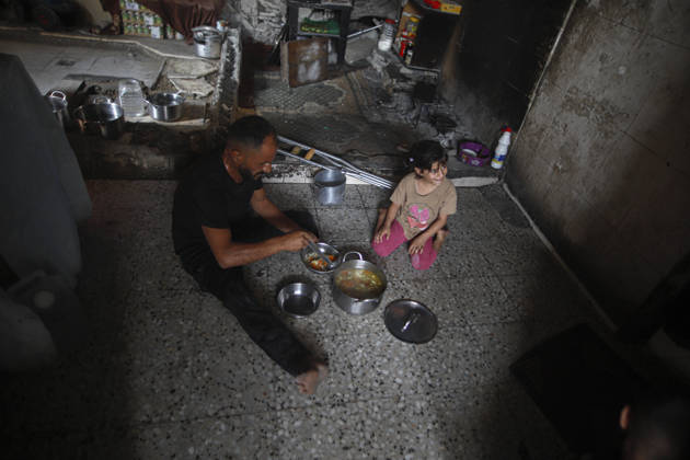Gaza Palestinians Food Shortages 2026 A Palestinian man and a young child sit on the floor of a damaged home to eat beside metal bowls and cooking pots in Jabalia Refugee Camp, northern Gaza Strip, Palestine, on October 24, 2026. The UN says widespread damage, displacement and food shortages have left families across Gaza heavily dependent on humanitarian assistance, with food distributions reduced in October amid funding constraints. Jabalia Gaza Strip Palestinian Territories Copyright: xRamezxHabboubx
