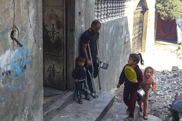 Gaza Palestinians Food Shortages 2026 A Palestinian man using crutches stands in a doorway as children pass through a damaged street in Jabalia Refugee Camp, northern Gaza Strip, Palestine, on October 24, 2026. The UN says widespread damage, displacement and food shortages have left families across Gaza heavily dependent on humanitarian assistance, with food distributions reduced in October amid funding constraints. Jabalia Gaza Strip Palestinian Territories Copyright: xRamezxHabboubx