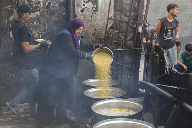 Gaza Palestinians Food Shortages 2026 A woman pours a large quantity of cooked food from one metal vessel into another at a charity kitchen in Jabalia Refugee Camp, northern Gaza Strip, Palestine, on October 24, 2026. Community kitchens remain a key source of food in Gaza, where UN humanitarian agencies reported cuts to cooked-meal distributions in October because of funding shortages. Jabalia Gaza Strip Palestinian Territories Copyright: xRamezxHabboubx