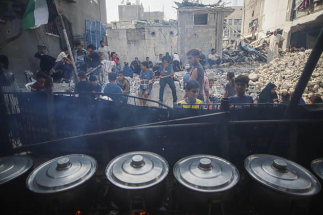 Gaza Palestinians Food Shortages 2026 Palestinians wait behind large cooking pots as food is prepared over an open flame at a charity kitchen in Jabalia Refugee Camp, northern Gaza Strip, Palestine, on October 24, 2026. Community kitchens remain a key source of food in Gaza, where UN humanitarian agencies reported cuts to cooked-meal distributions in October because of funding shortages. Jabalia Gaza Strip Palestinian Territories Copyright: xRamezxHabboubx