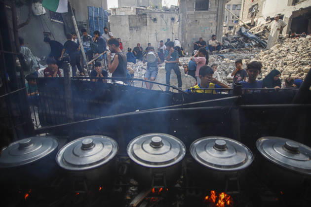 Gaza Palestinians Food Shortages 2026 Palestinians wait behind large cooking pots as food is prepared over an open flame at a charity kitchen in Jabalia Refugee Camp, northern Gaza Strip, Palestine, on October 24, 2026. Community kitchens remain a key source of food in Gaza, where UN humanitarian agencies reported cuts to cooked-meal distributions in October because of funding shortages. Jabalia Gaza Strip Palestinian Territories Copyright: xRamezxHabboubx