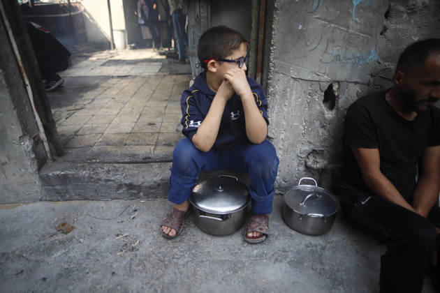 Gaza Palestinians Food Shortages 2026 A Palestinian child sits with a pot outside a damaged building, with another person seated nearby in Jabalia Refugee Camp, northern Gaza Strip, Palestine, on October 24, 2026. The UN says widespread damage, displacement and food shortages have left families across Gaza heavily dependent on humanitarian assistance, with food distributions reduced in October amid funding constraints. Jabalia Gaza Strip Palestinian Territories Copyright: xRamezxHabboubx