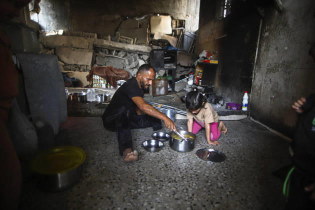 Gaza Palestinians Food Shortages 2026 A Palestinian man and a young child sit on the floor of a damaged home to eat beside metal bowls and cooking pots in Jabalia Refugee Camp, northern Gaza Strip, Palestine, on October 24, 2026. The UN says widespread damage, displacement and food shortages have left families across Gaza heavily dependent on humanitarian assistance, with food distributions reduced in October amid funding constraints. Jabalia Gaza Strip Palestinian Territories Copyright: xRamezxHabboubx
