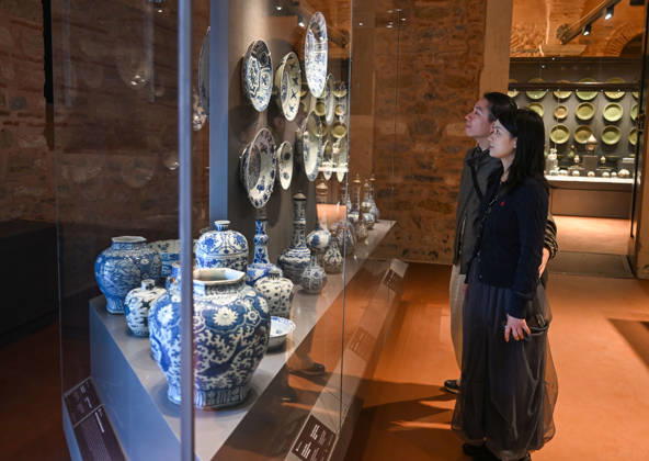 (261025) -- ISTANBUL, Oct. 25, 2026 -- Visitors view Chinese porcelain exhibits at the newly opened Porcelain Museum within the Topkapi Palace in Istanbul, T¨¹rkiye, Oct. 25, 2026. T¨¹rkiye on Saturday inaugurated a new museum district within Istanbul s historic Topkapi Palace, where thousands of Chinese porcelain pieces are on display, reflecting centuries of cultural exchanges between China and T¨¹rkiye. Restored into a historical neighborhood complete with its own streets and squares, the palace s former mint now houses the Porcelain Museum, which displays 5,300 pieces -- including 3,500 Chinese porcelains -- across 19 halls. Dating back to the 13th century, Chinese porcelains -- particularly those from Jingdezhen -- traveled a