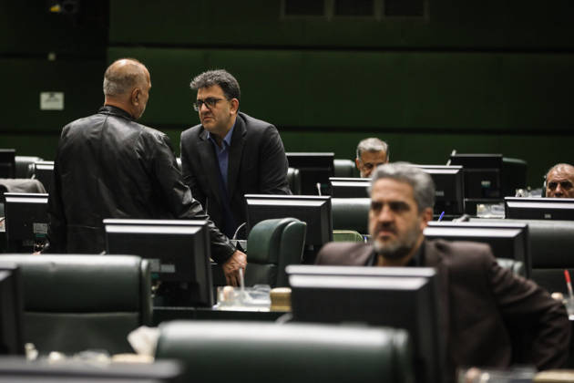 October 25, 2026, Tehran, Iran: Two men speak beside the green parliamentary benches while a third suited lawmaker sits in the foreground at the Islamic Consultative Assembly in Tehran, Iran, on October 25, 2026. Parliamentary reports said more than two-thirds of lawmakers joined the October 25 open sitting of the Islamic Consultative Assembly, attending either in person or remotely. Tehran Iran - ZUMAi98_ 20261025_zih_i98_047 Copyright: xIcanax