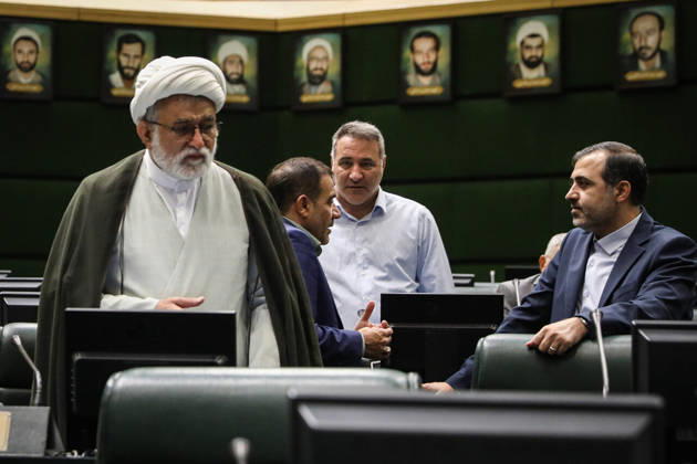 October 25, 2026, Tehran, Iran: A gray-bearded cleric in a white turban stands beside two suited men talking among the parliamentary benches at the Islamic Consultative Assembly in Tehran, Iran, on October 25, 2026. Parliamentary reports said more than two-thirds of lawmakers joined the October 25 open sitting of the Islamic Consultative Assembly, attending either in person or remotely. Tehran Iran - ZUMAi98_ 20261025_zih_i98_063 Copyright: xIcanax