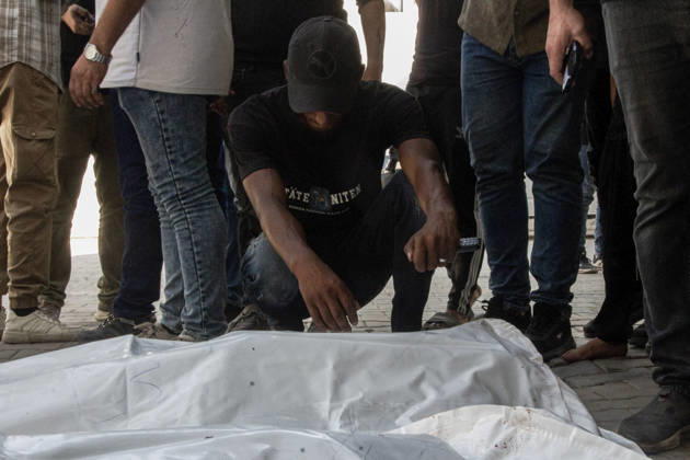 Gaza Israeli University Strike 2026 A Palestinian mourner crouches beside a white body bag while others stand nearby ahead of a funeral in Gaza City, Palestine, on October 25, 2026. According to information provided by local sources, three Islamic University guards, Ashraf Dahlan, Shadi Abu Ataya and Sami Baroud, were killed and others injured in an Israeli strike on the university campus in western Gaza City. Palestinian media reported that a second drone strike hit the campus after an earlier attack injured several people and prompted the university to suspend activities. Gaza Gaza Strip Palestinian Territories Copyright: xHassanxSalemx