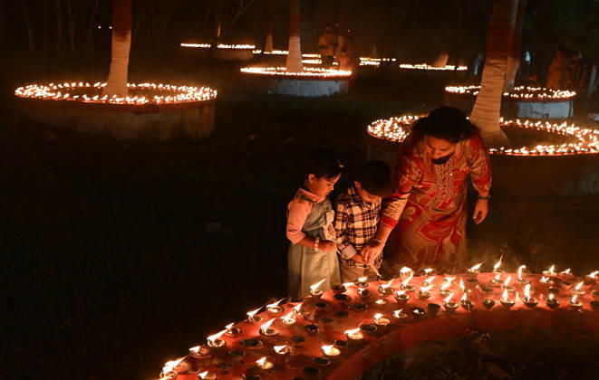 October 25, 2026, Mumbai, Maharashtra, India: A woman (R) helps her children to light earthen lamp on the occasion of Sharad Purnima (full moon) celebration in Mumbai. Sharad Purnima, also known as the Full Moon Festival, marks the end of the monsoon season. devotees observe fasting and meditate on the full moon night, Goddess Lakshmi, the deity of wealth, is worshipped on this day as it is believed to be her birthday. praying to her is said to bring good luck and prosperity in the life of devotees. Mumbai India - ZUMAs197 20261025_aab_s197_019 Copyright: xAshishxVaishnavx