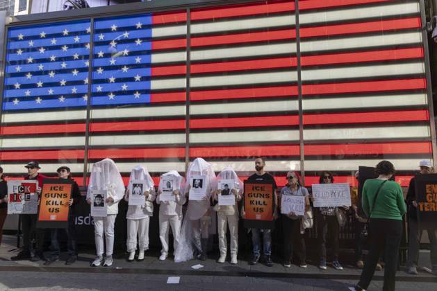 October 25, 2026, New York, New York, USA: Demonstrators with the anti-gun violence organization Gays Against Guns protest under the Times Square US Army Recruiting Station LED American flag to denounce U.S. Immigration and Customs Enforcement (ICE) and President Trump s immigrant detention and mass deportation policies. Protesters hold signs that read ICE GUNS KILL US. People dressed in white shrouds are Human Beings, memorializing people killed by gun violence from Federal immigration agents by holding signs with their images and names. New York USA  - ZUMAr174 20261025_znp_r174_013 Copyright: xGinaxMxRandazzox