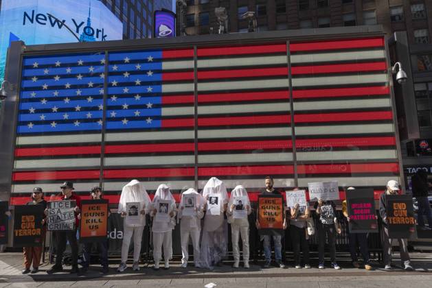 October 25, 2026, New York, New York, USA: Demonstrators with the anti-gun violence organization Gays Against Guns protest under the Times Square US Army Recruiting Station LED American flag to denounce U.S. Immigration and Customs Enforcement (ICE) and President Trump s immigrant detention and mass deportation policies. Protesters hold signs that read END GUN TERROR ICE IS A HATE CRIME ICE GUNS KILL US DISARM BOGUS PATRIOTS. People dressed in white shrouds are Human Beings, memorializing people killed by gun violence from Federal immigration agents by holding signs with their images and names. New York USA  - ZUMAr174 20261025_znp_r174_006 Copyright: xGinaxMxRandazzox