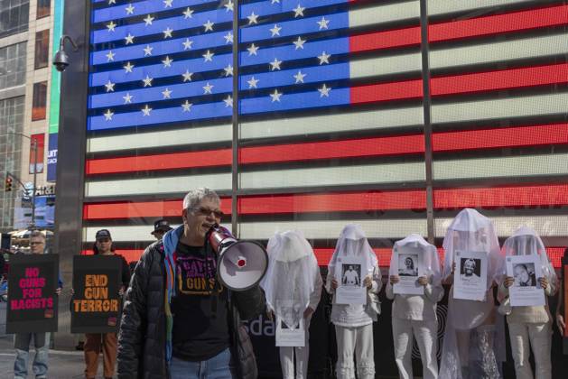 October 25, 2026, New York, New York, USA: Demonstrators with the anti-gun violence organization Gays Against Guns protest under the Times Square US Army Recruiting Station LED American flag to denounce U.S. Immigration and Customs Enforcement (ICE) and President Trump s immigrant detention and mass deportation policies. People dressed in white shrouds are Human Beings, memorializing people killed by gun violence from Federal immigration agents by holding signs with their images and names. Protesters chant holding signs that read NO GUNS FOR RACISTS END GUN TERROR. New York USA  - ZUMAr174 20261025_znp_r174_019 Copyright: xGinaxMxRandazzox