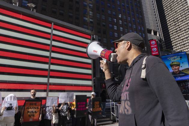 October 25, 2026, New York, New York, USA: JAY W. WALKER, President of Gays Against Guns leads chants at a demonstration under the Times Square US Army Recruiting Station LED American flag to denounce U.S. Immigration and Customs Enforcement (ICE) and President Trump s immigrant detention and mass deportation policies. People dressed in white shrouds are Human Beings, memorializing people killed by gun violence from Federal immigration agents by holding signs with their images and names. Protesters hold signs that read ICE GUNS KILL US KILLED BY ICE DISARM BOGUS PATRIOTS END GUN TERROR. New York USA - ZUMAr174 20261025_znp_r174_004 Copyright: xGinaxMxRandazzox
