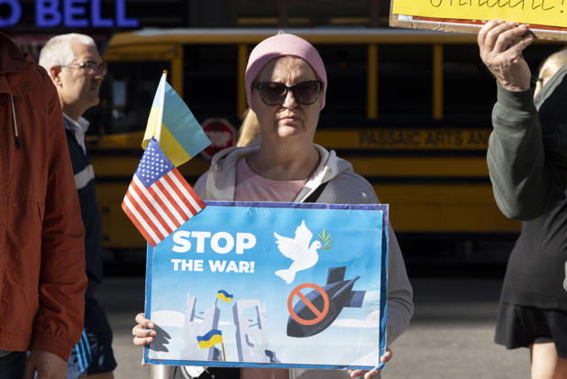 October 25, 2026, New York, New York, USA: A demonstrator holding Ukrainian and American flags and a sign that reads STOP THE WAR! with images of a dove and a red circle slash over a bomb stands with a group of protesters in Times Square. New York USA - ZUMAr174 20261025_znp_r174_028 Copyright: xGinaxMxRandazzox