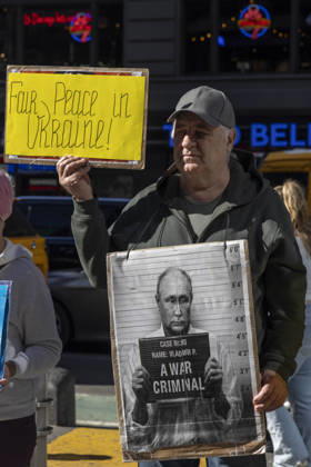 October 25, 2026, New York, New York, USA: A demonstrator stands with a group of protesters in Times Square holding signs that read Fair Peace in Ukraine! and a sign with an image of President of Russia V. Putin in a mugshot that reads A WAR CRIMINAL. New York USA - ZUMAr174 20261025_znp_r174_027 Copyright: xGinaxMxRandazzox